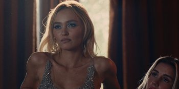 Movie still from “The Idol” (2023), directed by Sam Levinson – A beautiful blonde haired woman wearing a silver top; Close Up shot, Over the shoulder angle