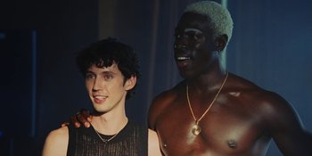 Movie still from “The Idol” (2023), directed by Sam Levinson – Two young men standing next to each other; Medium shot, Low angle