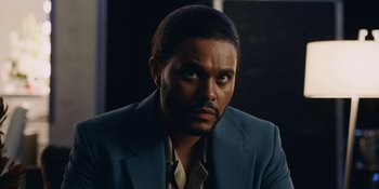Movie still from “The Idol” (2023), directed by Sam Levinson – A person wearing a suit and tie; Close Up shot, Low angle