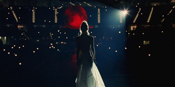 Movie still from “The Idol” (2023), directed by Sam Levinson – A woman in a white dress standing in front of a red moon; Wide shot, Low angle