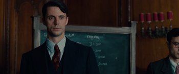 Movie still from “The Imitation Game” (2014), directed by Morten Tyldum – A man in a suit and tie standing in front of a chalkboard; Close Up shot, Over the shoulder angle