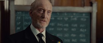Movie still from “The Imitation Game” (2014), directed by Morten Tyldum – An older man wearing a suit and tie in front of a chalkboard; Close Up shot, Over the shoulder angle