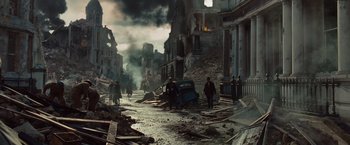 Two men are walking down the street near a destroyed building