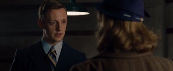 Movie still from “The Imitation Game” (2014), directed by Morten Tyldum – A man wearing a suit and tie talking to a woman wearing a hat; Close Up shot, Over the shoulder angle