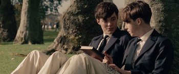 Movie still from “The Imitation Game” (2014), directed by Morten Tyldum – A man sitting on the ground with a book in his hands; Medium shot, Over the shoulder angle