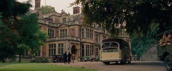 Movie still from “The Imitation Game” (2014), directed by Morten Tyldum – An old fashioned bus parked in front of a large building; Extreme Wide shot, Low angle