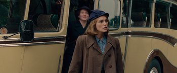 Movie still from “The Imitation Game” (2014), directed by Morten Tyldum – A woman in a brown coat and a blue hat standing next to a bus; Medium shot, Over the shoulder angle