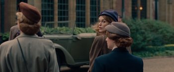 Movie still from “The Imitation Game” (2014), directed by Morten Tyldum – A woman wearing a hat standing next to another woman in front of an old car; Medium shot, Over the shoulder angle
