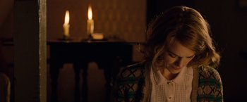 Movie still from “The Imitation Game” (2014), directed by Morten Tyldum – A woman sitting in front of a candle in a dark room; Medium shot, High angle