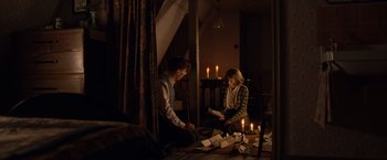 Movie still from “The Imitation Game” (2014), directed by Morten Tyldum – A man and a woman sitting on the floor in front of candles; Wide shot, High angle