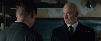 Movie still from “The Imitation Game” (2014), directed by Morten Tyldum – A man in a suit and tie standing next to another man in a suit and tie; Close Up shot, Over the shoulder angle