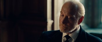 Movie still from “The Imitation Game” (2014), directed by Morten Tyldum – An older man wearing a suit and tie; Close Up shot, Over the shoulder angle