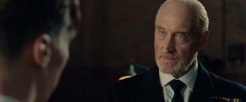 Movie still from “The Imitation Game” (2014), directed by Morten Tyldum – An older man wearing a suit and tie; Close Up shot, Over the shoulder angle