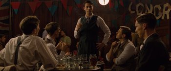Movie still from “The Imitation Game” (2014), directed by Morten Tyldum – A group of people sitting at a table with drinks; Medium shot, Over the shoulder angle