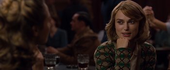 Movie still from “The Imitation Game” (2014), directed by Morten Tyldum – A woman sitting in front of a group of people at a table; Close Up shot, Over the shoulder angle