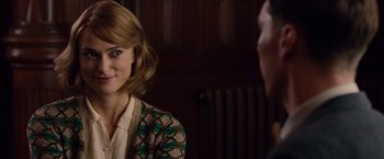 Movie still from “The Imitation Game” (2014), directed by Morten Tyldum – A young woman smiles at the camera while a young man looks at her; Close Up shot, Over the shoulder angle