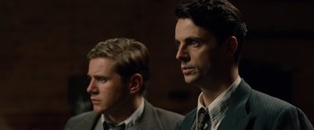 Movie still from “The Imitation Game” (2014), directed by Morten Tyldum – Two men in suits and ties looking at the camera; Close Up shot, Over the shoulder angle
