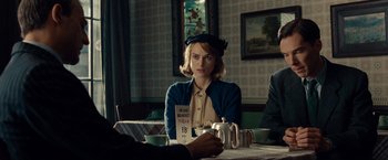 Movie still from “The Imitation Game” (2014), directed by Morten Tyldum – A woman sitting at a table with a cup of coffee; Medium shot, Over the shoulder angle