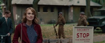 Movie still from “The Imitation Game” (2014), directed by Morten Tyldum – A woman standing in front of a building with a man in the background; Medium shot, Over the shoulder angle