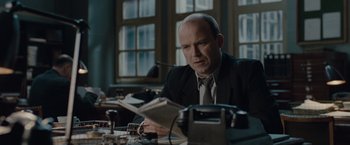 Movie still from “The Imitation Game” (2014), directed by Morten Tyldum – A man sitting at a table reading a newspaper; Medium shot, High angle