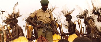 Movie still from “The Last King of Scotland” (2006), directed by Kevin Macdonald – A man holding a rifle while standing next to another man; Medium shot, Low angle