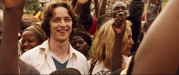 Movie still from “The Last King of Scotland” (2006), directed by Kevin Macdonald – A group of people standing in front of each other; Medium shot, Over the shoulder angle