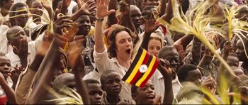 Movie still from “The Last King of Scotland” (2006), directed by Kevin Macdonald – A group of people in a crowd waving flags; Medium shot, High angle