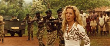 Movie still from “The Last King of Scotland” (2006), directed by Kevin Macdonald – A group of people in uniform with guns and a woman in a zebra striped shirt; Medium shot, Over the shoulder angle