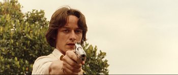 Movie still from “The Last King of Scotland” (2006), directed by Kevin Macdonald – A man holding a gun in his right hand; Close Up shot, Low angle