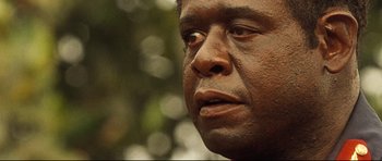 Movie still from “The Last King of Scotland” (2006), directed by Kevin Macdonald – A man's face with a blurry background; Close Up shot, Over the shoulder angle