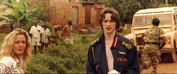 Movie still from “The Last King of Scotland” (2006), directed by Kevin Macdonald – A man in a military uniform standing in front of a brick building; Medium shot, Over the shoulder angle