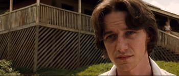 Movie still from “The Last King of Scotland” (2006), directed by Kevin Macdonald – A person's face in front of a building; Close Up shot, Low angle