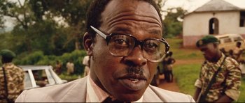 Movie still from “The Last King of Scotland” (2006), directed by Kevin Macdonald – An older man wearing glasses and a suit; Close Up shot, Low angle