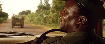 Movie still from “The Last King of Scotland” (2006), directed by Kevin Macdonald – A person in a car holding a steering wheel; Close Up shot, Over the shoulder angle