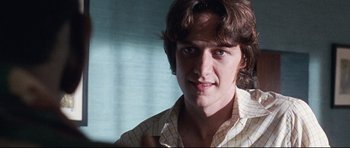 Movie still from “The Last King of Scotland” (2006), directed by Kevin Macdonald – A young man in a checkered shirt is smiling; Close Up shot, Low angle