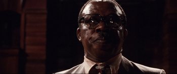 Movie still from “The Last King of Scotland” (2006), directed by Kevin Macdonald – An older man wearing glasses and a tie; Close Up shot, Low angle