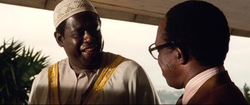 Movie still from “The Last King of Scotland” (2006), directed by Kevin Macdonald – Two men talking to each other while standing next to each other; Close Up shot, Over the shoulder angle