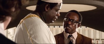 Movie still from “The Last King of Scotland” (2006), directed by Kevin Macdonald – Two men are standing next to each other talking; Close Up shot, Low angle