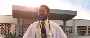 Movie still from “The Last King of Scotland” (2006), directed by Kevin Macdonald – A man in a white lab coat with a stethoscope around his neck; Close Up shot, Low angle