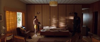 Movie still from “The Last King of Scotland” (2006), directed by Kevin Macdonald – A man standing in front of a bed in a room; Wide shot, Low angle