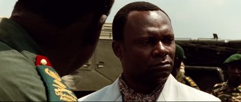 Movie still from “The Last King of Scotland” (2006), directed by Kevin Macdonald – A man in a white jacket is talking to another man; Close Up shot, Over the shoulder angle