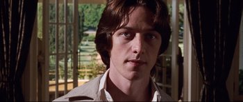 Movie still from “The Last King of Scotland” (2006), directed by Kevin Macdonald – A man with long brown hair wearing a white shirt; Close Up shot, Low angle