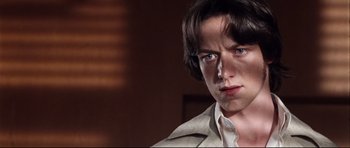 Movie still from “The Last King of Scotland” (2006), directed by Kevin Macdonald – A man with long dark hair wearing a white shirt; Close Up shot, Over the shoulder angle