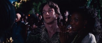 Movie still from “The Last King of Scotland” (2006), directed by Kevin Macdonald – A person with a crowd in the background; Close Up shot, Over the shoulder angle