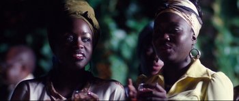 Movie still from “The Last King of Scotland” (2006), directed by Kevin Macdonald – Two women are standing in front of a tree; Close Up shot, Over the shoulder angle
