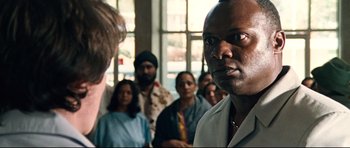 Movie still from “The Last King of Scotland” (2006), directed by Kevin Macdonald – A group of people standing in front of a window; Close Up shot, Over the shoulder angle