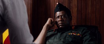 Movie still from “The Last King of Scotland” (2006), directed by Kevin Macdonald – A man in a military uniform is talking on a cell phone; Close Up shot, Low angle