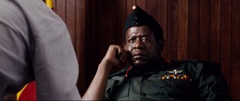 Movie still from “The Last King of Scotland” (2006), directed by Kevin Macdonald – A man in a military uniform sitting in front of a wooden wall; Close Up shot, Low angle