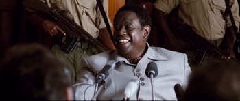 Movie still from “The Last King of Scotland” (2006), directed by Kevin Macdonald – A man sitting in front of microphones in a room; Close Up shot, Over the shoulder angle