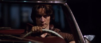 Movie still from “The Last King of Scotland” (2006), directed by Kevin Macdonald – A man sitting in the driver's seat of a car; Close Up shot, Low angle